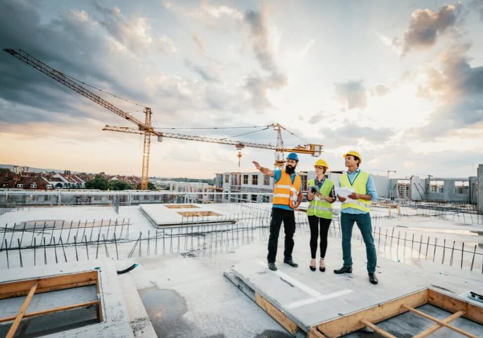 Employees working on construction site, wearing protective equipment and discussing next construction phase - full length models visible on the image