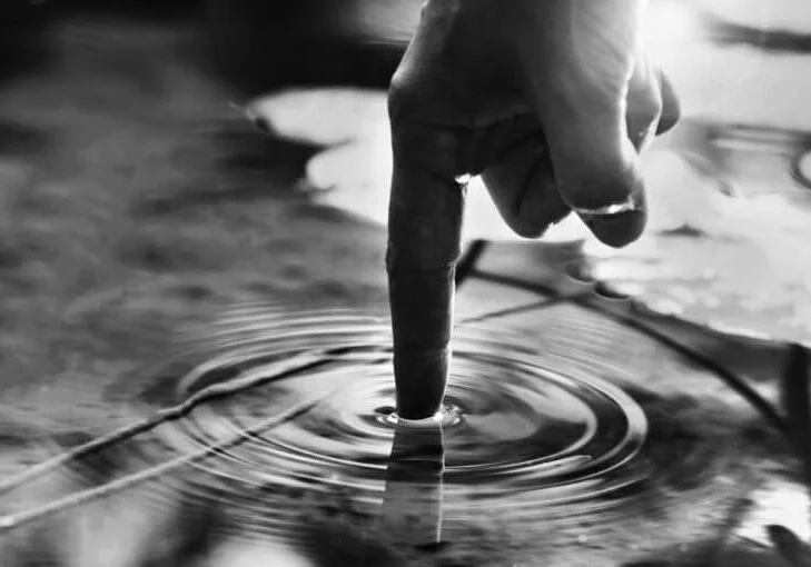 person touches the water with his hand