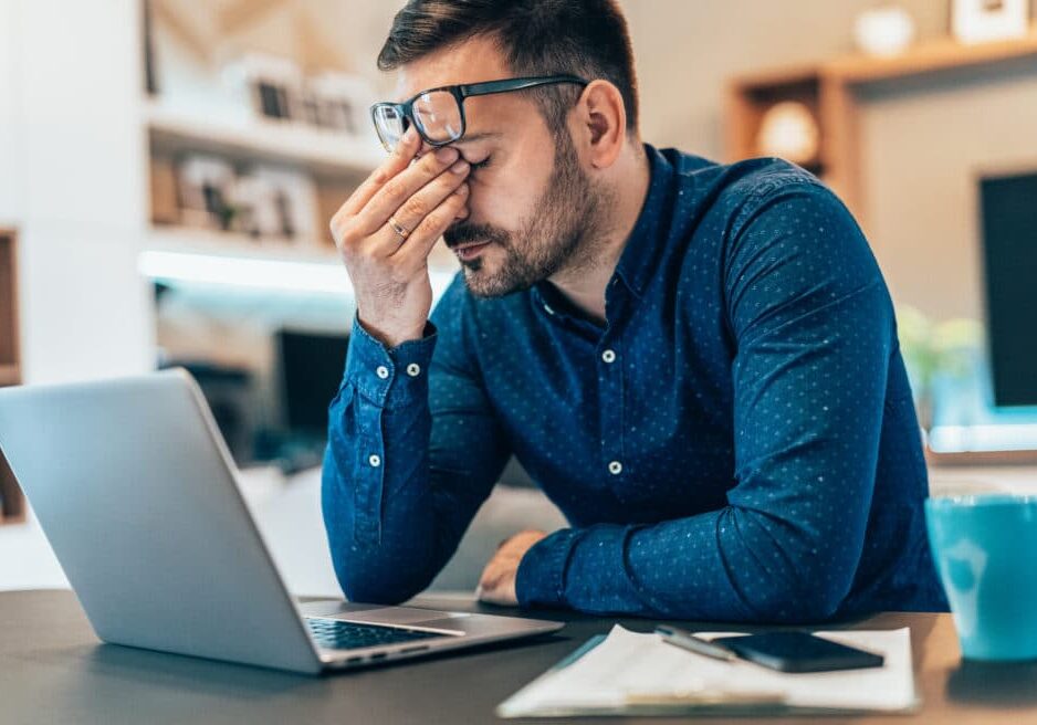 Home office Tired young businessman working at home using lap top and looking Anxious