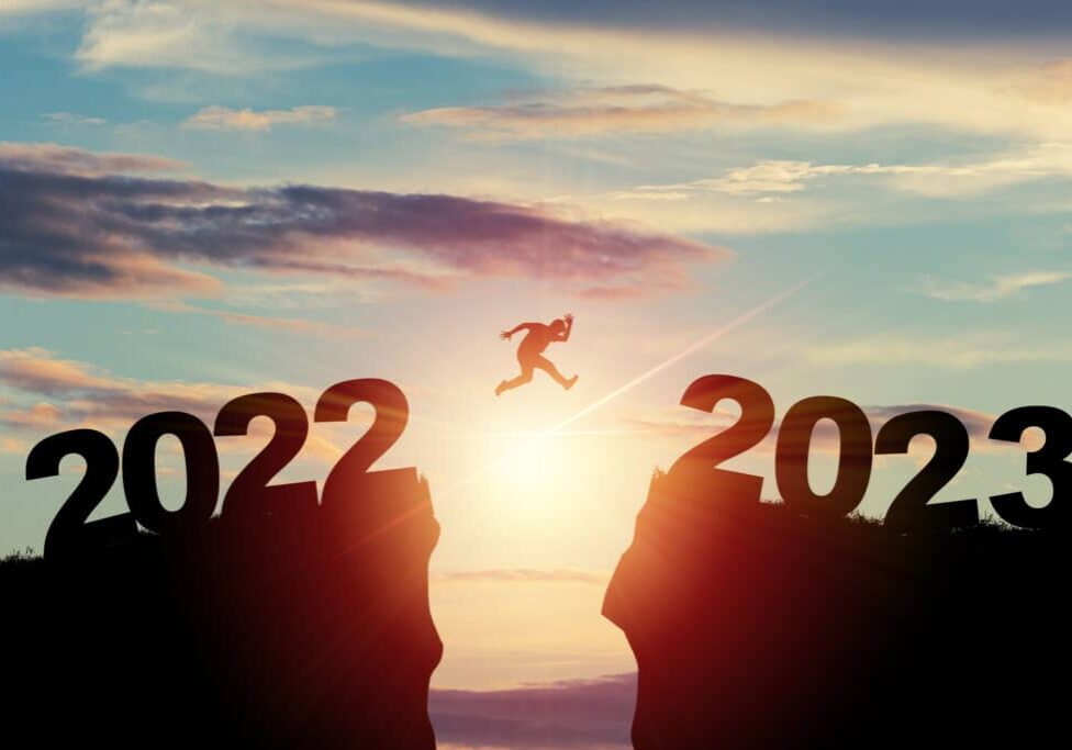 Welcome merry Christmas and happy new year in 2023,Silhouette Man jumping from 2022 cliff to 2023 cliff with cloud sky and sunlight.