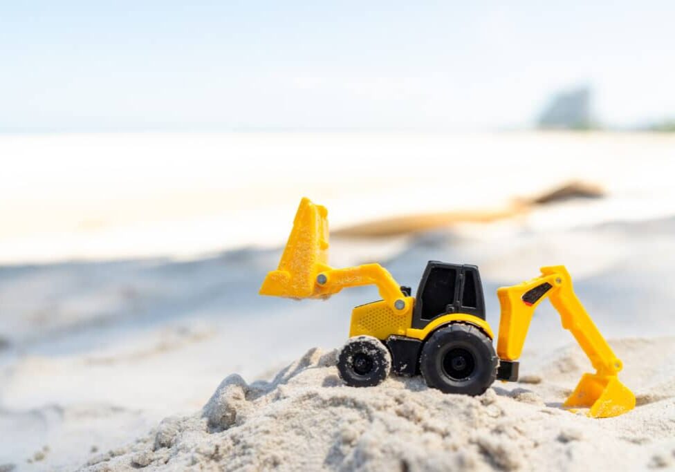 Backhoe toy yellow plastic on beach sand