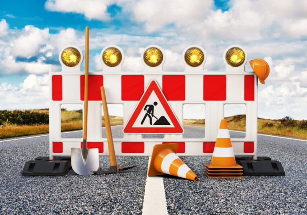 Street barrier with shovel, traffic sign, traffic cone and safety helmet on the road 3D rendering